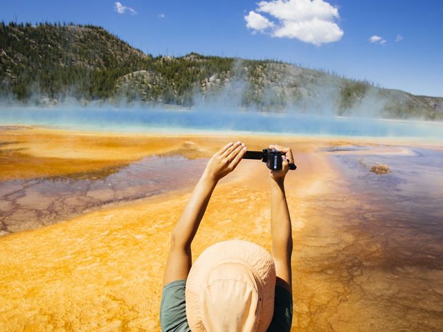 A tourist takes a photo of the Grand Prismatic Spring in Yellowstone National Park.