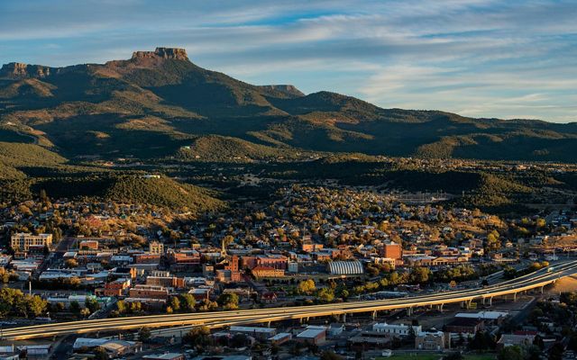 A town with an elevated highway passing through and a rocky peak in the distance.