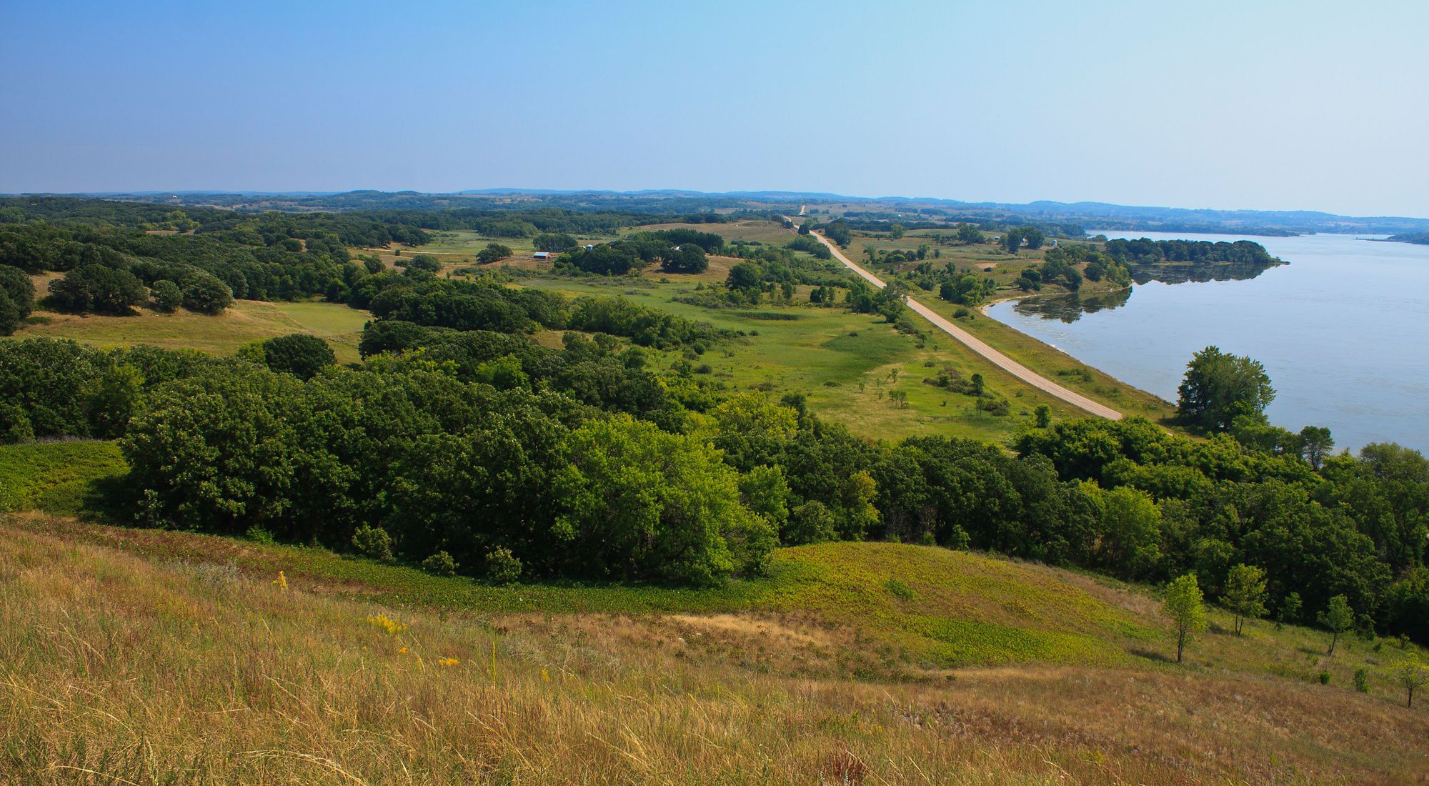 Green and yellow prairies next to a lake. 